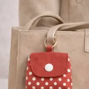 Pocket Bag Abril rojo con lunares blancos colgado en bolso beige